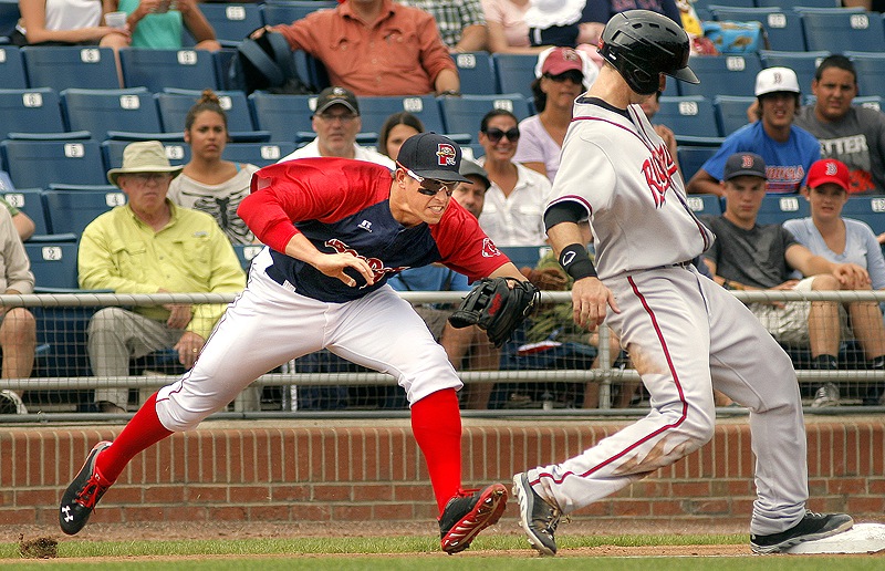Third baseman Garin Cecchini of the Portland Sea Dogs swipes at Ryan Lollis of the Richmond Flying Squirrels, who hustled back after advancing on a single.