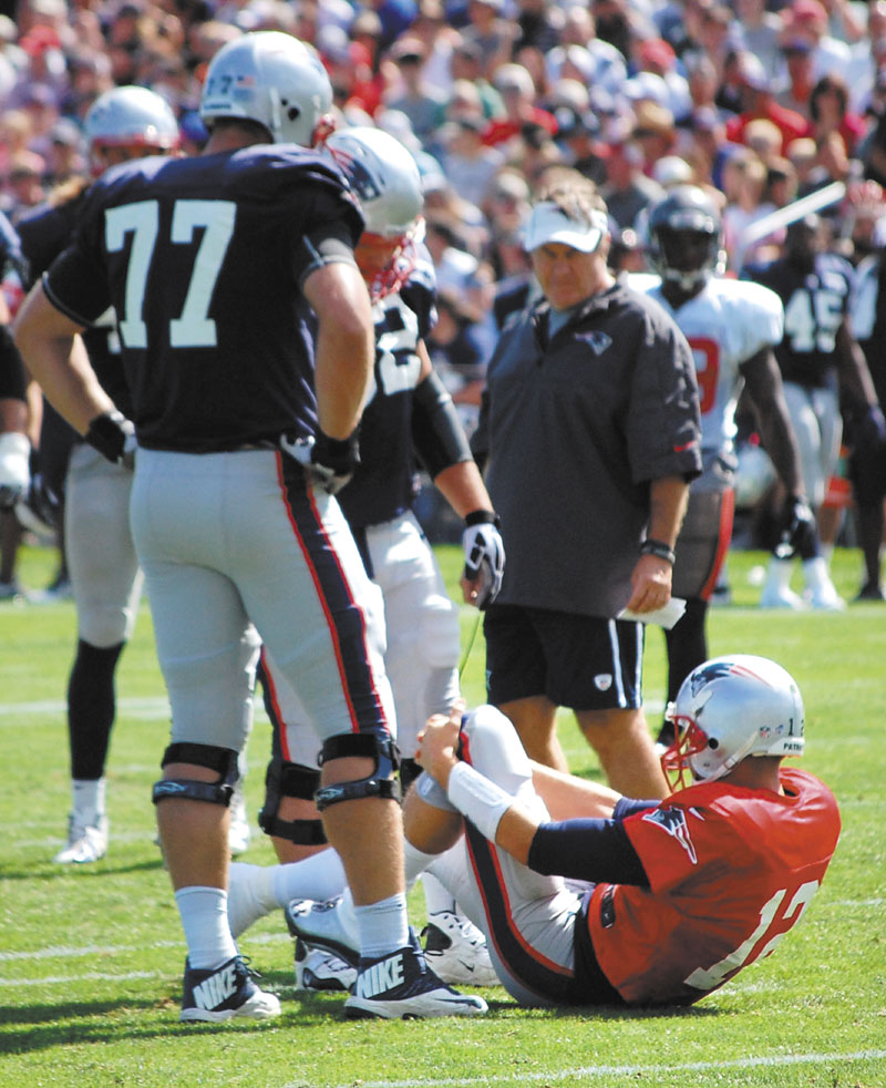 OH, NO: New England Patriots quarterback Tom Brady grabs his left knee, while left tackle Nate Solder, left, and head coach Bill Belichick look on after Brady suffered what a source said was a sprained left knee during a joint workout with the Tampa Bay Buccaneers on Wednesday in Foxborough, Mass.