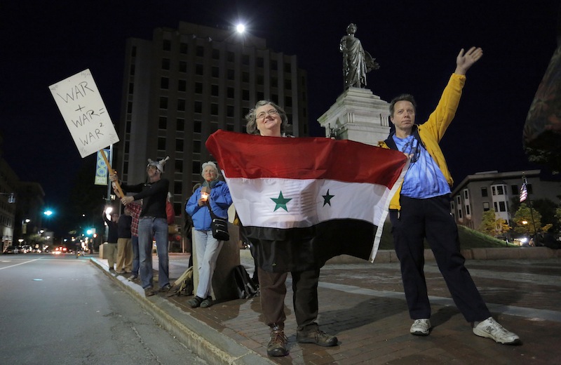 Lucinda McGinn, of Westbrook, and her husband Peter McGinn, hold a Syrian Flag and wave to passing traffic as part of a gathering in Monument Square on Monday evening, September 9, 2013, to protest the proposed military action in Syria by the United States.