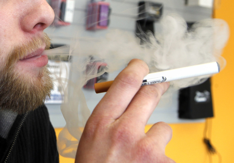 A sales associate demonstrates the use of an electronic cigarette, which emits smokelike vapor, in Aurora, Colo.