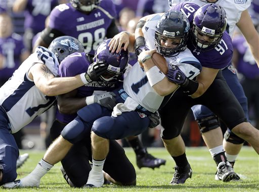 HANGING IN: Maine quarterback Marcus Wasilewski (7) is tackled by Northwestern defensive end Ifeadi Odenigbo (7) and Tyler Scott (97) during the Black Bears’ 35-21 loss Saturday in Evanston, Ill.
