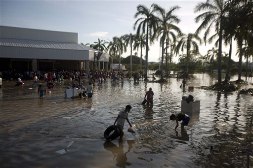 People wade through waist-high water in a store's parking, looking for valuables, south of Acapulco, in Punta Diamante, Mexico, on Wednesday. Mexico was hit by the one-two punch of twin storms over the weekend, and the storm that soaked Acapulco on Sunday – Manuel – re-formed into a tropical storm Wednesday, threatening to bring more flooding to the country's northern coast.