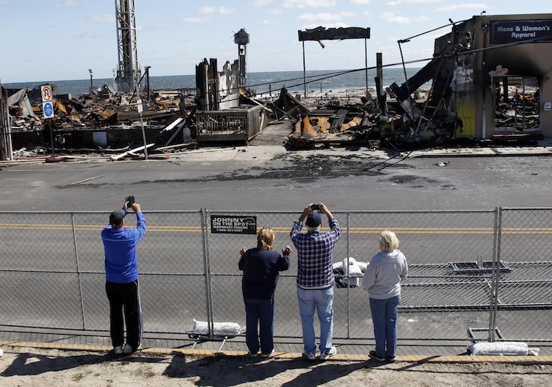 People take photographs of the charred rubble in Seaside Park, N.J., Tuesday, Sept. 17, 2013, after a fire last Thursday that started near a frozen custard stand in Seaside Park, quickly spread north into neighboring Seaside Heights. More than 50 businesses in the two towns were destroyed. The massive boardwalk fire in New Jersey began accidentally, the result of an electrical problem, an official briefed on the investigation said Tuesday. (AP Photo/Mel Evans)