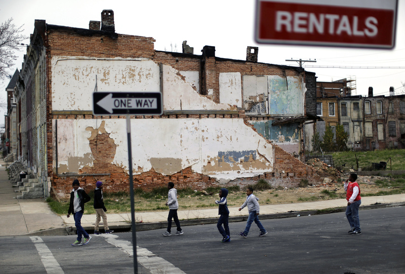 A group of boys walks past a partially collapsed row house in Baltimore. The nation's poverty rate stood still at 15 percent in 2012, the sixth straight year that it has failed to improve.