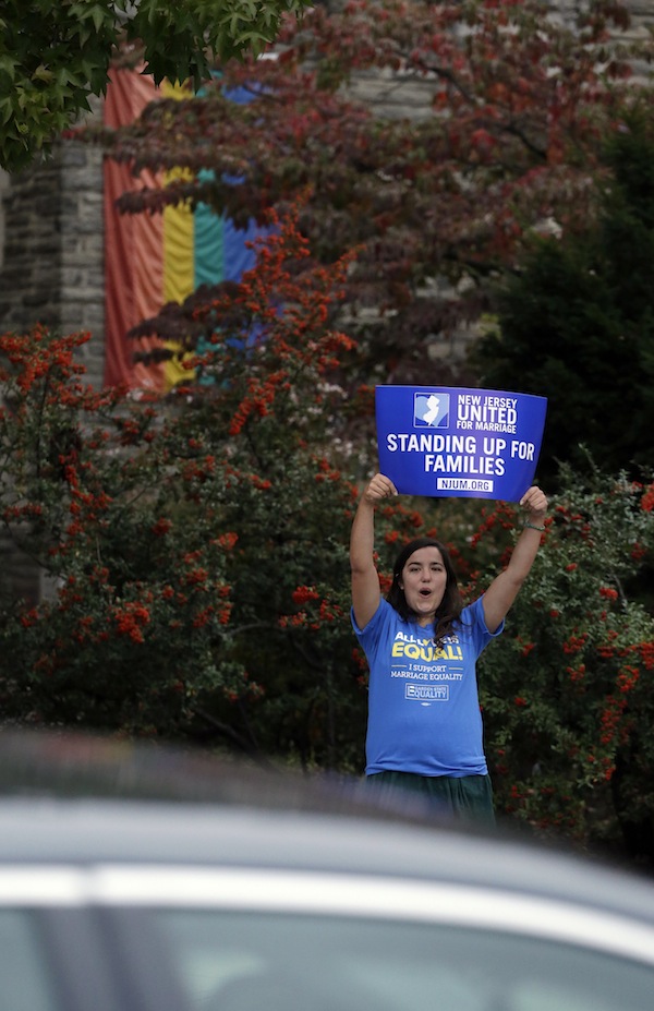 Alex Nikazmerad, 24, of North Plainfield, N.J., shouts at a passing vehicle before a rally hosted by Garden State Equality in Montclair, N.J., hours after same-sex marriages were made legal as of Oct. 21 by a state judge on Friday.