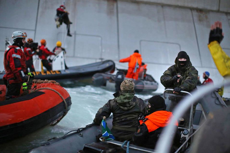 A Russian Coast guard officer is seen pointing a gun at a Greenpeace International activist as five activists attempt to climb the 'Prirazlomnaya,' an oil platform operated by Russian state-owned energy giant Gazprom in Russia's Pechora Sea. The activists were there to stop it from becoming the first to produce oil from the ice-filled waters of the Arctic.
