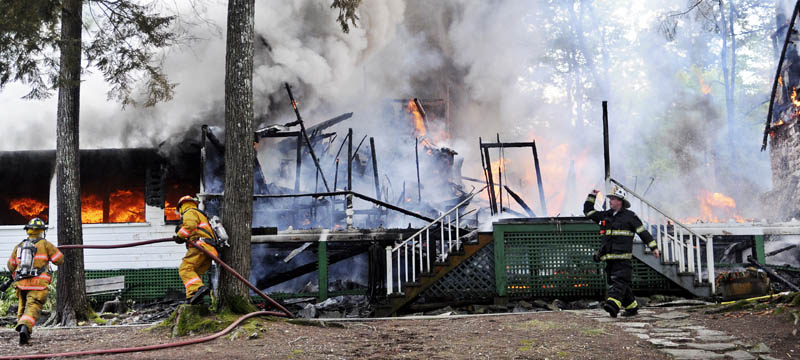 FIrefighters approach the Echo Lake Lodge Tuesday in Fayette. Rented as a private camp, the Lodge that was erected in 1937 was destroyed by fire.