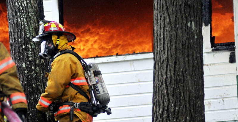 A firefighter approaches Echo Lake Lodge Tuesday in Fayette as it is destroyed by fire.