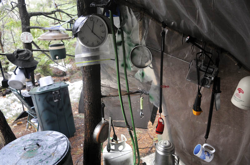 Coffee cups, lights and a clock hang under a tarp in Christopher Knight's camp Tuesday, April 9, 2013 in a remote, wooded section of Rome after police inspected the site where Knight is believed to have lived since the 1990s.