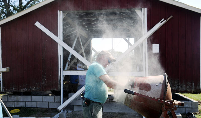 Greg Larravee adds concrete to a mixer Wednesday for the foundation of the black smith shop that volunteers at the Litchfield Fair are placing before the annual agricultural exhibition.