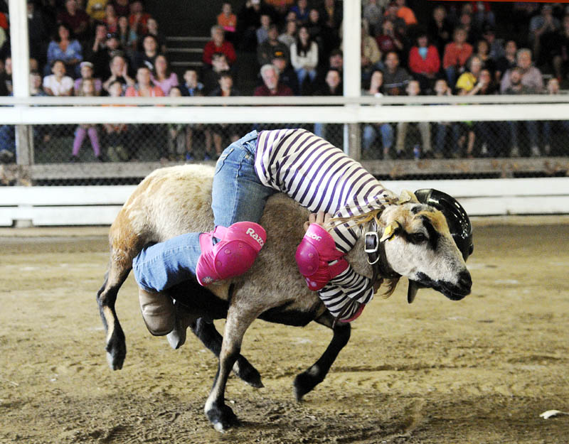 Savannah Hill, 8, rides a sheep today during the mutton bustin' contest at the Litchfield Fair. Hill tied for first place with Darcy Cram, 8.