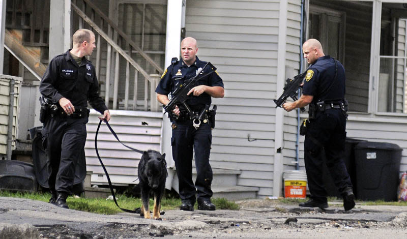 Cpl. G.J. Neagle of the Kennebec County Sheriff's Office, left, today attempts to track a man allegedly carrying a gun with his dog on Mount Vernon Avenue in Augusta, aongside Augusta police officers Don Whitten, center, and Peter Cloutier. Police gave chase following an alleged robbery on Boothby Street.