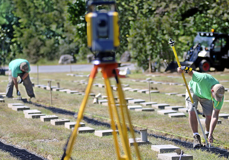 Josh Luce, right, uses satellite coordinates to mark headstones that Nick Cushman set Monday at the Maine Veterans' Memorial Cemetery in Augusta. The Farley & Son Landscaping employees reset several hundred stones at the cemetery.