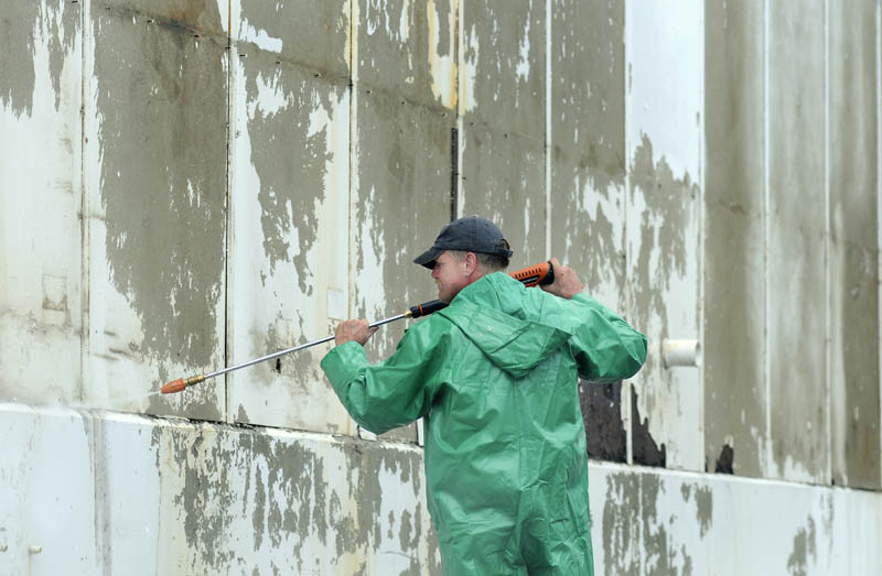 Skeeter Arnold blasts paint Monday off the loading dock of a warehouse in South Gardiner. A crew from Tim Dennett Property Management was taking advantage of wet conditions to pressure wash the paint off the building before applying new coats later in the week.