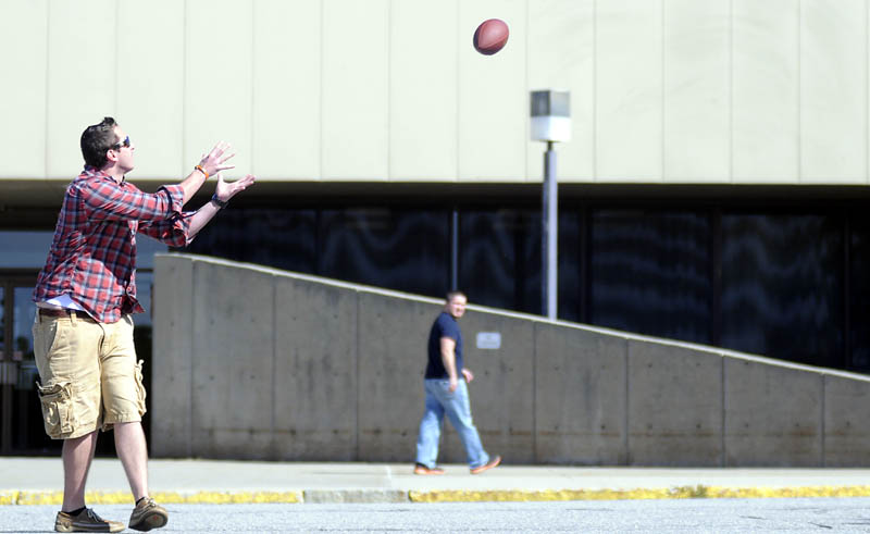 Zach Montell collects a pass Monday while playing catch outside the Central Maine Commerce Center in Augusta. Montell, Jordan Cloutier, right, Aaron Howard and Chris Owen took a break from their sales jobs at Access Worldwide to chuck the pigskin the morning after the Patriots' first football victory of the season. "They should have won by more than two points," Cloutier remarked.