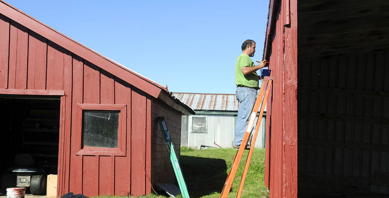 Eric Dickerson applies a coat of paint Thursday to an out building at O'Donnell's Farm in Monmouth. Dickerson said the weather conditions and forecast were perfect for touching up the barn and other structures at the organic beef farm. "It's going to be so beautiful, it looks like we're going to get it done soon," Dickerson said.