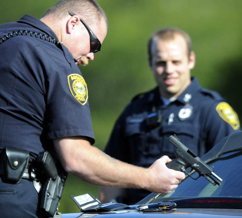 Augusta Police Department Sgt. Chris Shaw inspects a pistol Tuesday that officers took from a man following a road rage incident in Augusta. A man allegedly displayed the pistol after two woman confronted him about his driving, according to police.