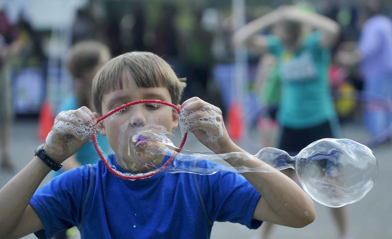 Charlie Frost, 9, of Canaan, blows bubbles through a form made from a giant pipe cleaner at Inland Hospital's Family Fun Day in Waterville today.