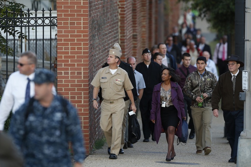 Military personnel and workers walk along the perimeter of the Washington Navy Yard Thursday, Sept. 19, 2013. The Washington Navy Yard began returning to nearly normal operations three days after it was the scene of a mass shooting in which a gunman killed 12 people. (AP Photo/Charles Dharapak)