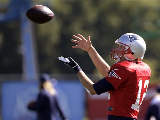 New England Patriots quarterback Tom Brady (12) catches a ball during a stretching and drills session before NFL football practice at the team's training facility in Foxborough, Mass., Wednesday.