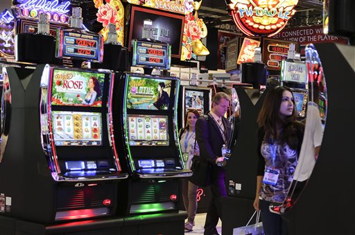 Gaming industry representatives stop to play various slot machines at the Global Gaming Expo on Wednesday in Las Vegas. Moving away from moving parts to video technology, the venerable slot machine is undergoing a generational shift.