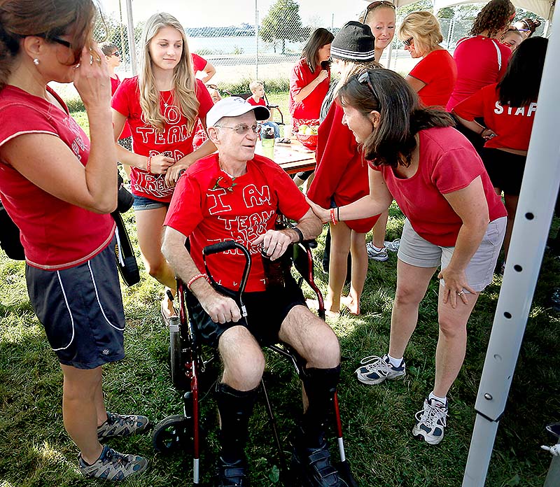 Jim Caldwell of Falmouth visits with friends and family before the start of the Walk to Defeat ALS in Portland on Saturday. Behind Caldwell is his daughter Sarah, 16.