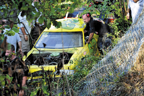 CRASH AND GO: Workers clear a fence and trees from the race car driven by Kyle Robinson, 15, of Clinton that went off the track, up a steep dirt embankment, through a wire fence and landed in a ditch Sunday at Unity Raceway. Robinson was not hurt and returned to race after repairs to the car were made.