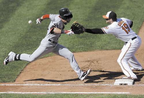 PAINFUL OUT: Boston’s Jacoby Ellsbury, left, runs toward first base as Baltimore first baseman Chris Davis reaches for a throw in the fourth inning Sunday in Baltimore. Ellsbury advanced to second base on a throwing error by catcher Steve Clevenger, Jarrod Saltalamacchia scored on the play and Davis left the game with an injury.