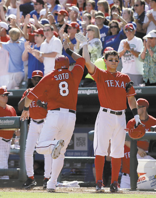 NICE JOB: Texas’ Geovany Soto (8) is congratulated by Ian Kinsler, right, at the dugout entrance after Soto scored on a Craig Gentry single against the Los Angeles Angels on Sunday in Arlington, Texas. A.J. Pierzynski also scored on the single by Gentry.