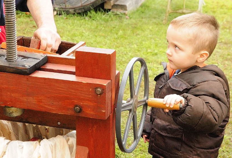 Rannon Rines, 3, of Greene, turns the handle on a cider press during AppleFest events last year at The Monmouth Museum. The events included fresh apples and apple pie for sale and a 5K road race earlier in the morning.