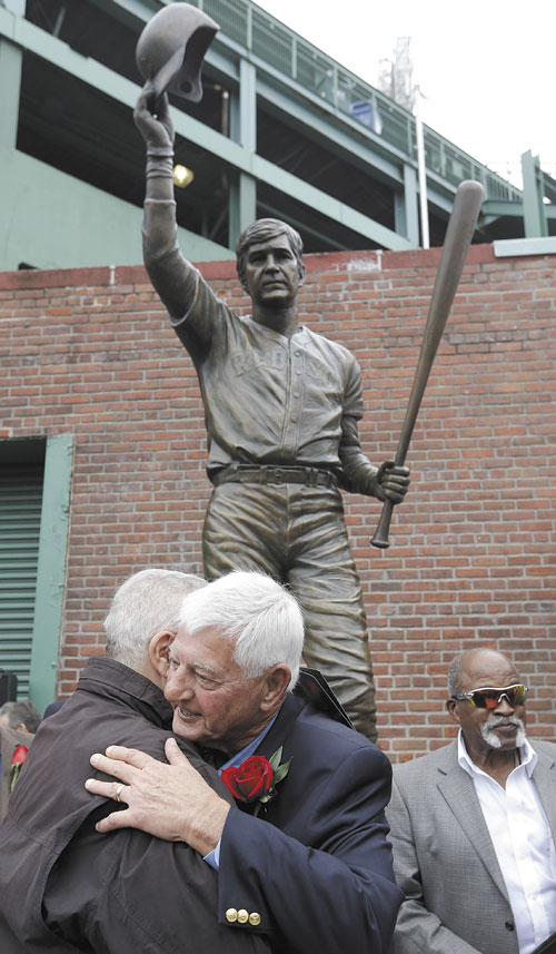 GREAT CAREER: Hall of Famer Carl Yastrzemski, center, hugs former Boston Red Sox’s Ted Lepcio, left, during a ceremony held to unveil a statue of Yastrzemski on Sunday at Fenway Park in Boston. Former Red Sox’s Luis Tiant stands behind right.