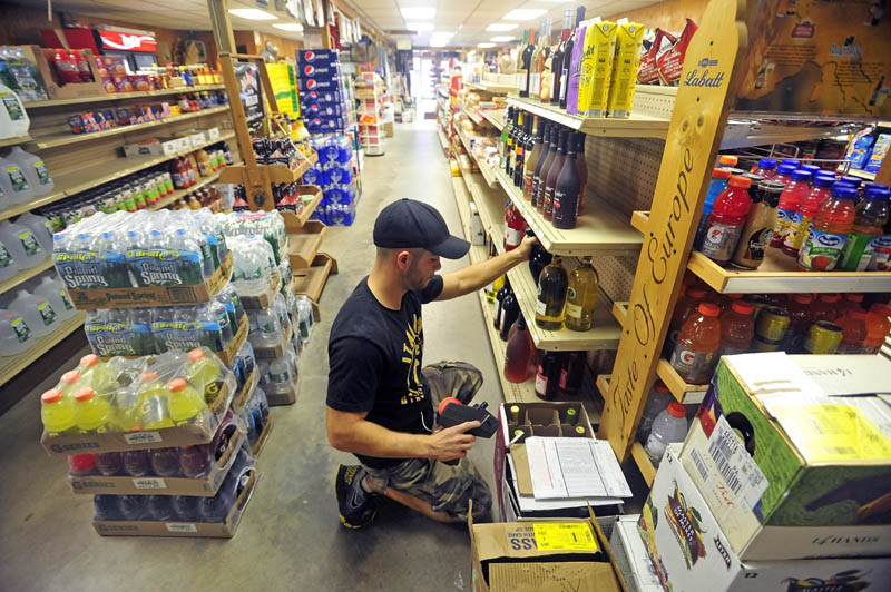 Berry stocks shelves with wine and other assortments of beverages during his afternoon shift at the family's general store in West Forks. He will later pack his gym bag and drive two and a half hours to Stockton Springs for two hours of intense training at Wyman's Boxing Club.