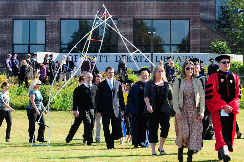 Rising Scholars and the professor that nominated them walk under a sculpture during the convocation at the University of Maine at Augusta today.