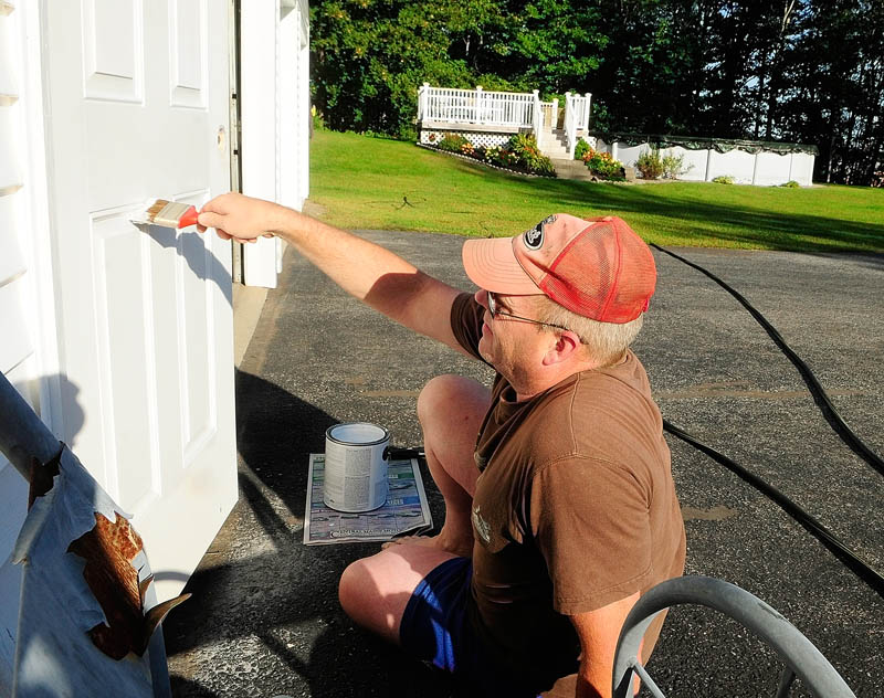 David Willman paints a door on Friday at his Augusta home on Old Belgrade Road, near the new MaineGeneral regional hospital. Willman said that it was just regular maintenance that he'd be doing anyway regardless of whether or not the house is for sale.