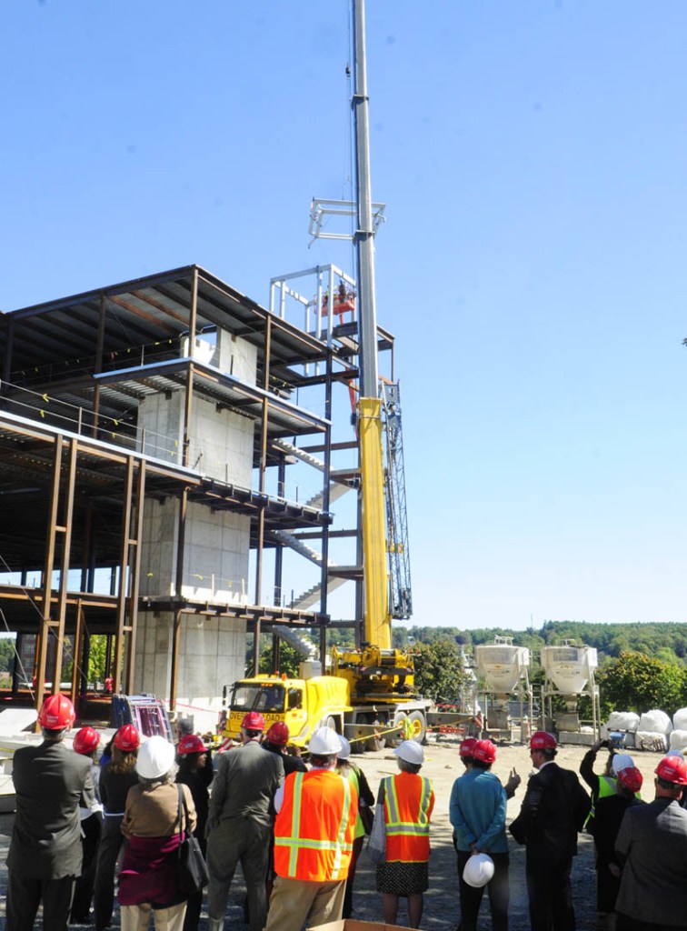 People watch as the last beam is swung into place.
