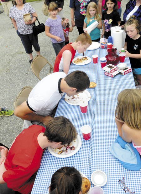 Spectators watch the pie-eating contest during Whitefield Community Day today in Whitefield. Tyler Pope, 32 of Whitefield, center, in white shirt, was the fastest of four contestants to eat three Table Talk pies without using his hands.