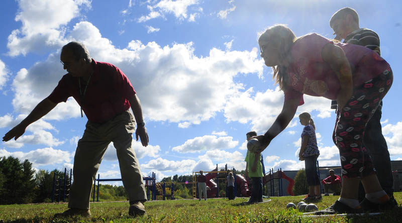 Raymond Fecteau, left, gives Adriana Yeaton, center, some advice on where to throw the metal ball, called a boule, during her pétanque game against Ian Gifford, right, on Friday at Farrington School in Augusta. Raymond and Lucette Fecteau, from Mill Park Pétanque group, taught a skills class in the traditional French game.