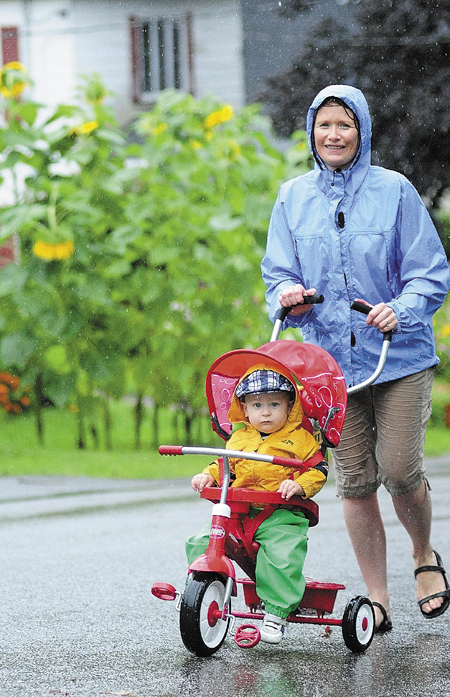 Oliver Gadebirk-St. Pierre, 14 months, gets pushed by his mother, Sine Gadebirk-St. Pierre, in the rain today in Hallowell. She said the rainy holiday weather wasn't going to interfere with a walk through their neighborhood. The National Weather Service reported that over two inches of rain fell at the Augusta State Airport through 2 p.m. today.
