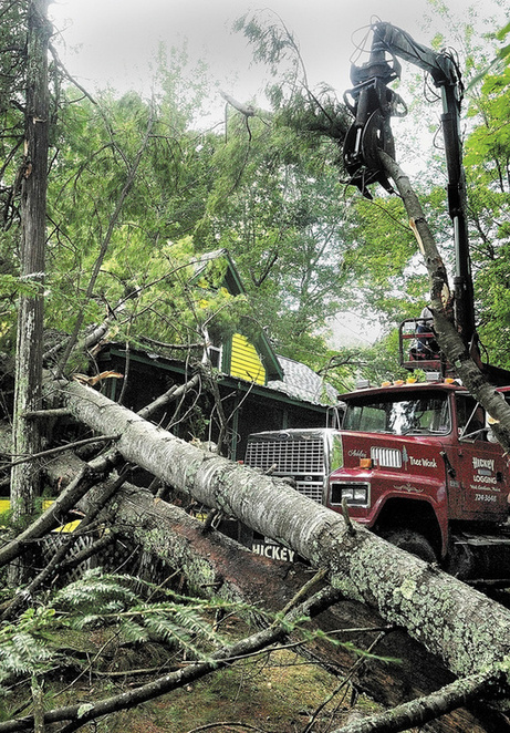 A crew from Hickey Logging cleans up several fallen trees on Thursday at a camp on the banks of Cobbossee Lake in West Gardiner. Several trees on the property were blown during a thunderstorm on Wednesday night. Owners Jack Boynton and Gail Andrews said that they'd been standing on the porch watching lightning over water when the trees fell right in front, but not on top, of the camp.