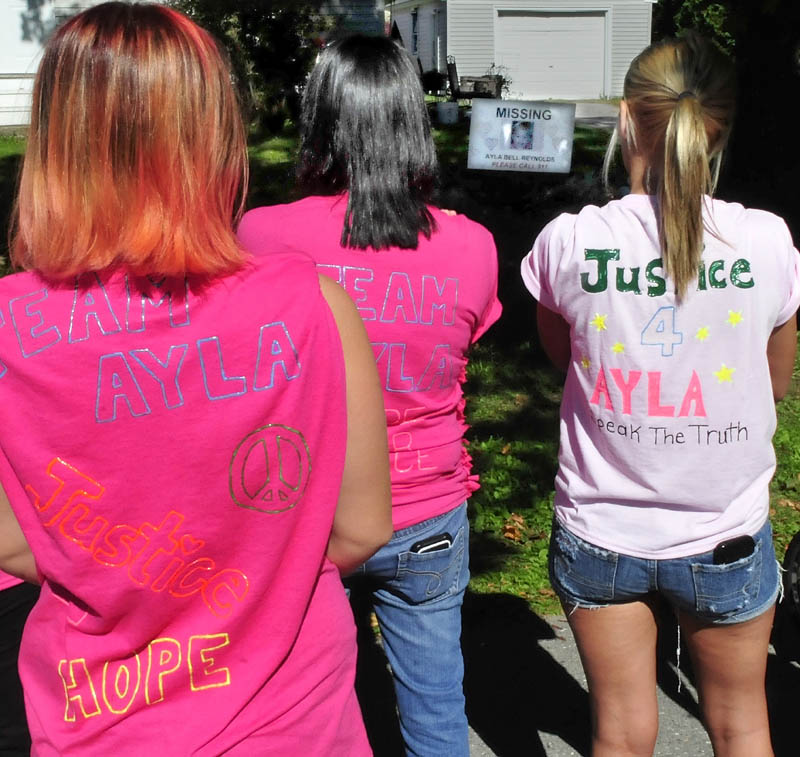 Wearing T-shirts in honor of Ayla Reynolds today, three of about two dozen participants in a walk pray for the missing toddler at the Violette Avenue home where she was reported missing in December 2011. In the background is a photograph of Ayla Reynolds.