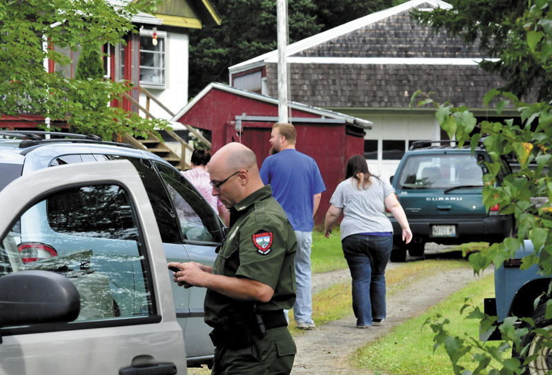 Game Warden Steven Couture prepares to search for Arthur Wakeman behind his residence in Benton on Thursday, as family members arrive at the home. Wakeman was reported missing Wednesday evening.