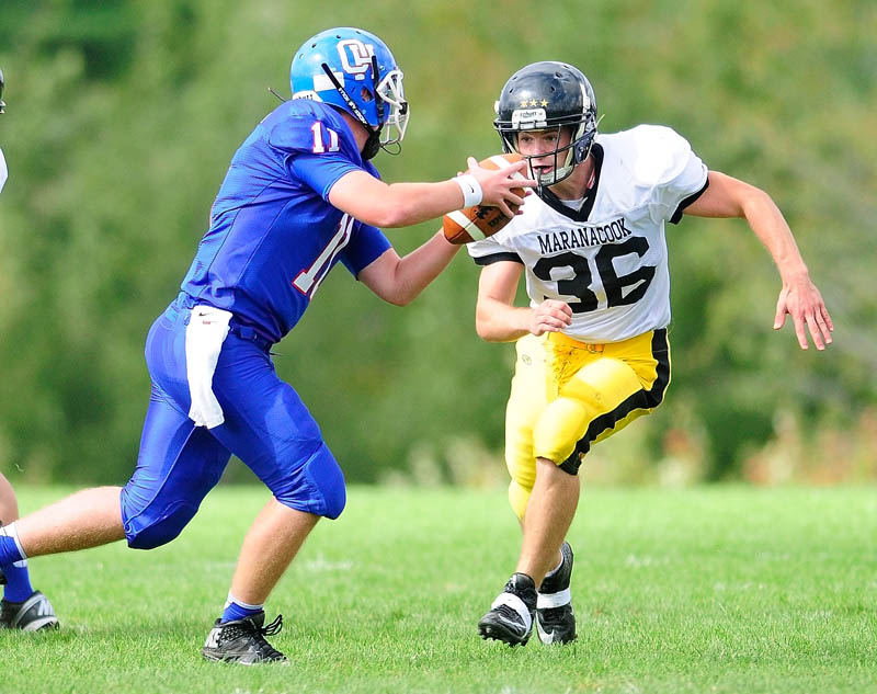 Oak Hill quarterback Parker Asselin tries to run away from Maranacook defensive end Simon Davis but got sacked on the play during a game on Saturday in Wales.