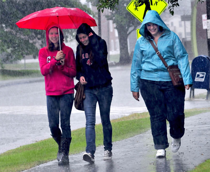 University of Maine at Farmington students Kristen Tarr, Anna Dowling and Jen Perry exit the student union in the rain today.