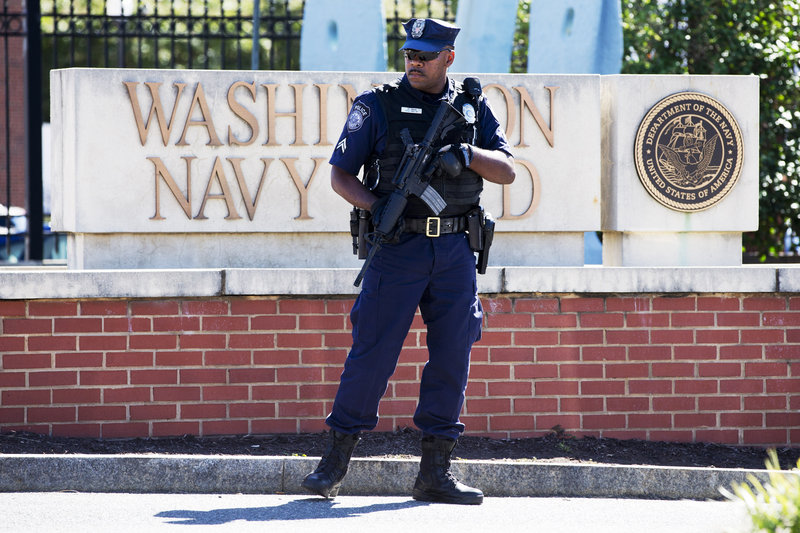 An armed officer who said he is with the Department of Defense, works near the gate at the Washington Navy Yard in Washington, D.C., on Tuesday, a day after a gunman launched an attack there.