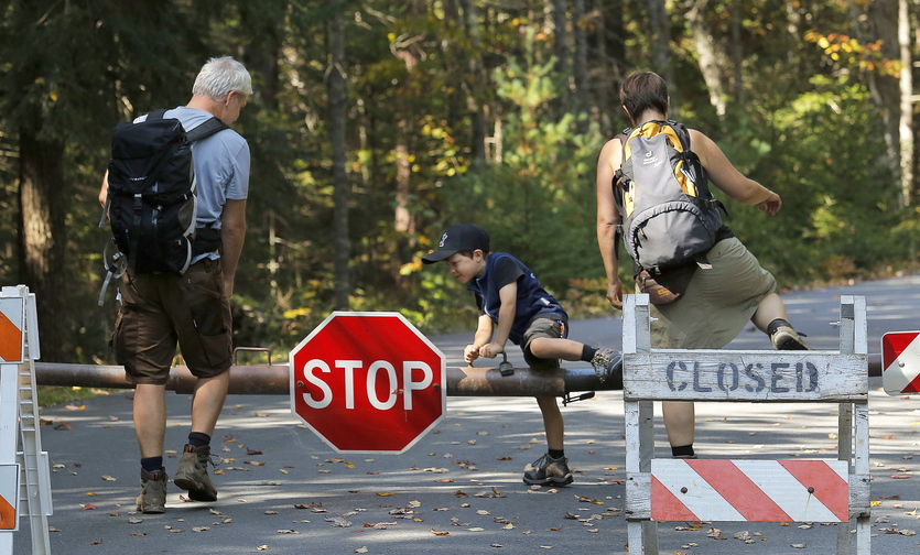 Titus Steinberg, 5, of Herne, Germany, hops over a gate at Acadia National Park’s Echo Lake in Southwest Harbor last Wednesday along with his parents, Oliver, at left, and Ramona. The family was one of a handful of visitors who wouldn’t let the government shutdown stop them from entering it.
