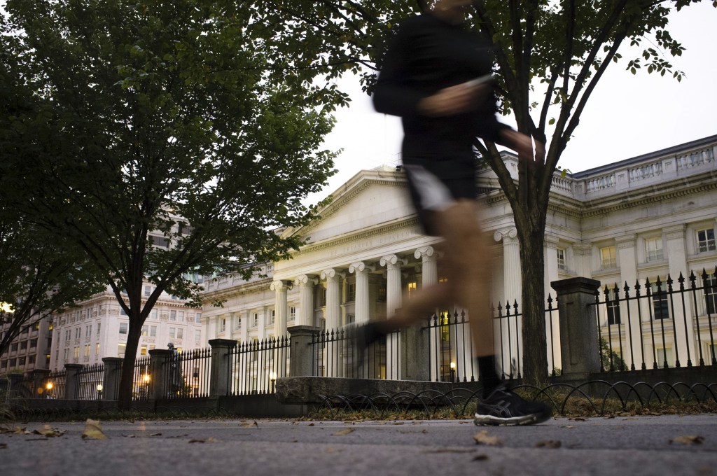 A jogger on an early morning run passes the U.S Treasury Building in Washington, Wednesday, Oct. 16, 2013, a day before the stalemate in Congress over the budget could cause the government to reach its borrowing limit.