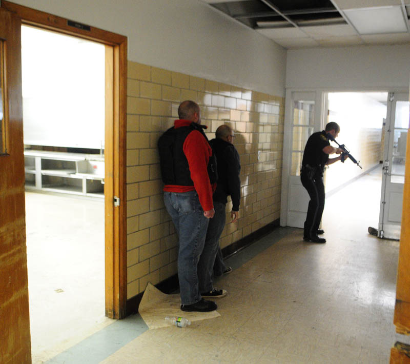 Augusta firefighter/paramedics Scott Sirois, left, and Rich Beaudoin stay low and close to the wall as they follow Augusta police patrolman Ben Murtiff down a hallway during a simulated school shooting incident Friday at the former Hodgkins Middle School in Augusta.