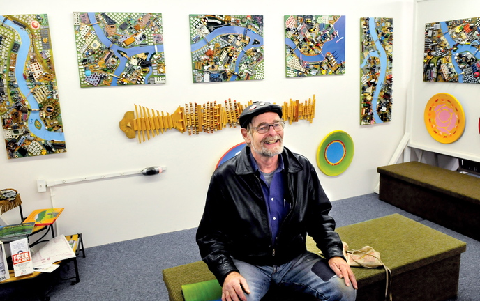 COLORFUL FELLOW: Artist Wally Warren speaks about his art including “City of Dreams” behind him at the Central Maine Artists Gallery in Skowhegan.