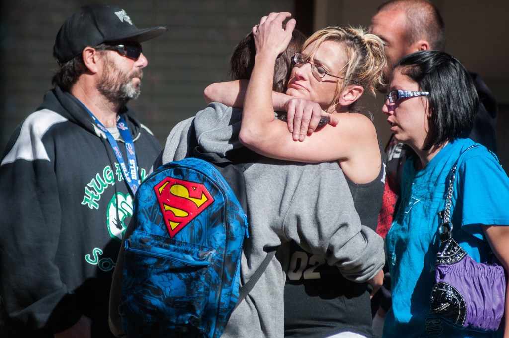 A Sparks Middle School student, back to camera, cries with family members after being released from an evacuation center Monday in Sparks Nev., after a shooting at Sparks Middle School.