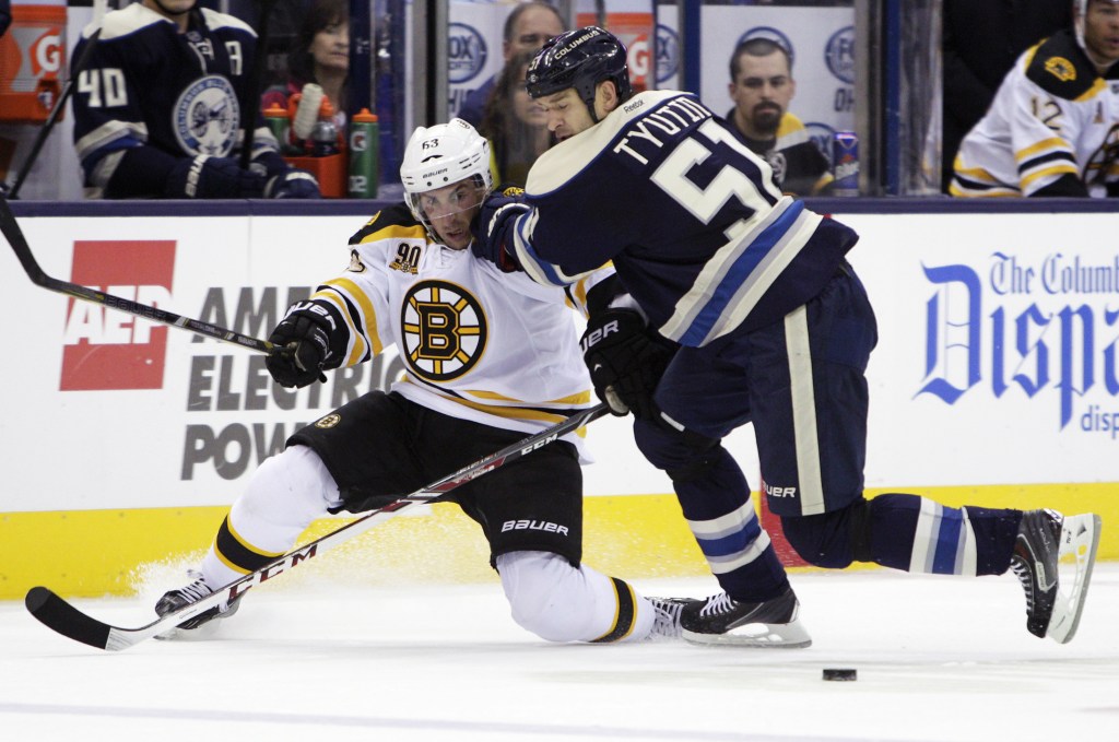 Columbus Blue Jackets’ Fedor Tyutin, right, checks Boston Bruins’ Brad Marchand away from the puck in the first period Saturday at Columbus, Ohio.